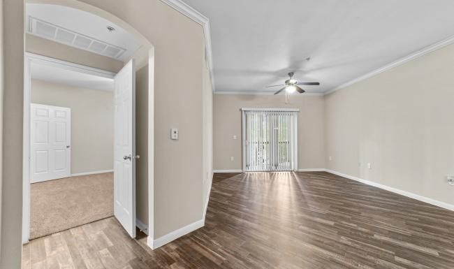 an empty living room with a wood floor and a ceiling fan
