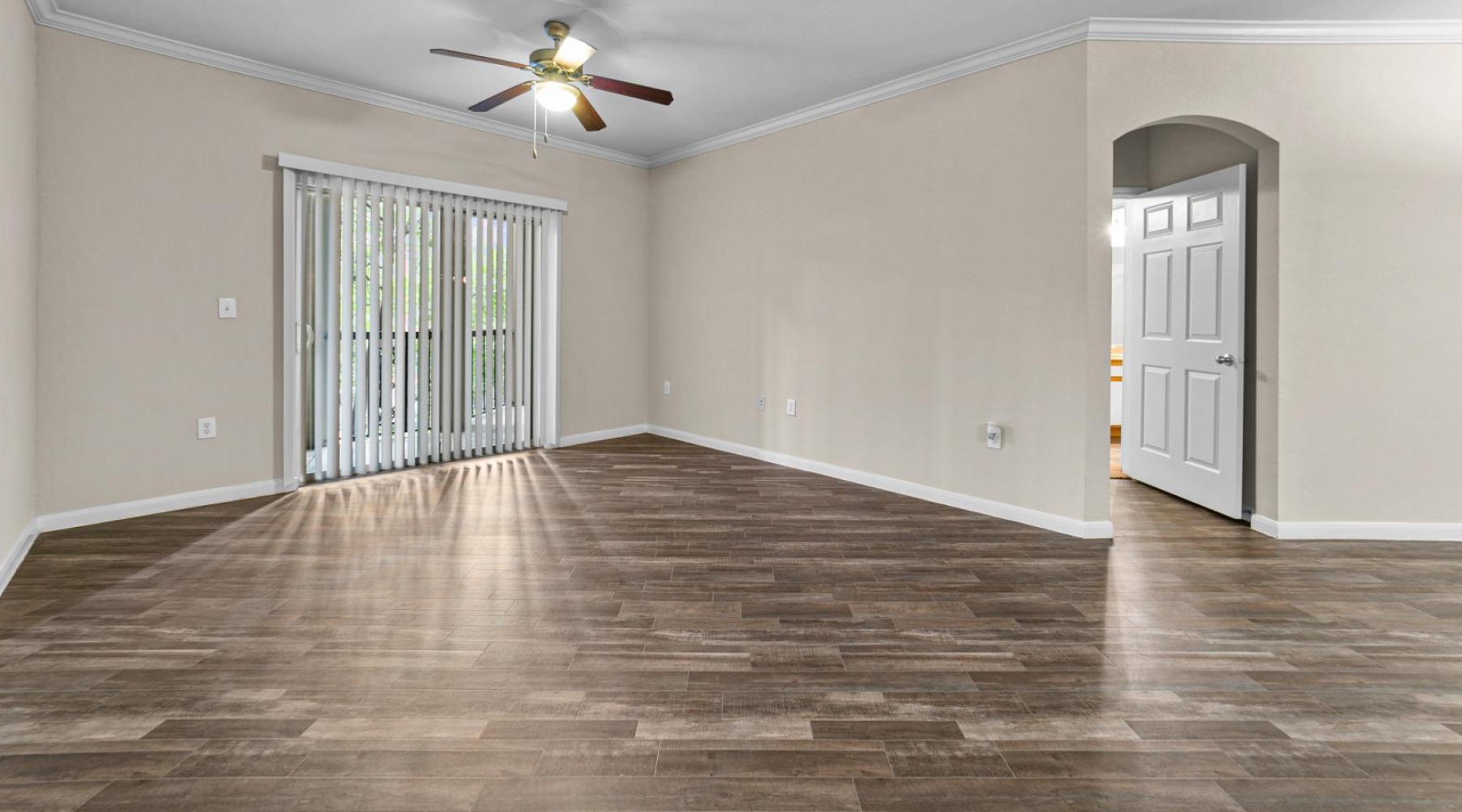 an empty living room with a wood floor and a ceiling fan